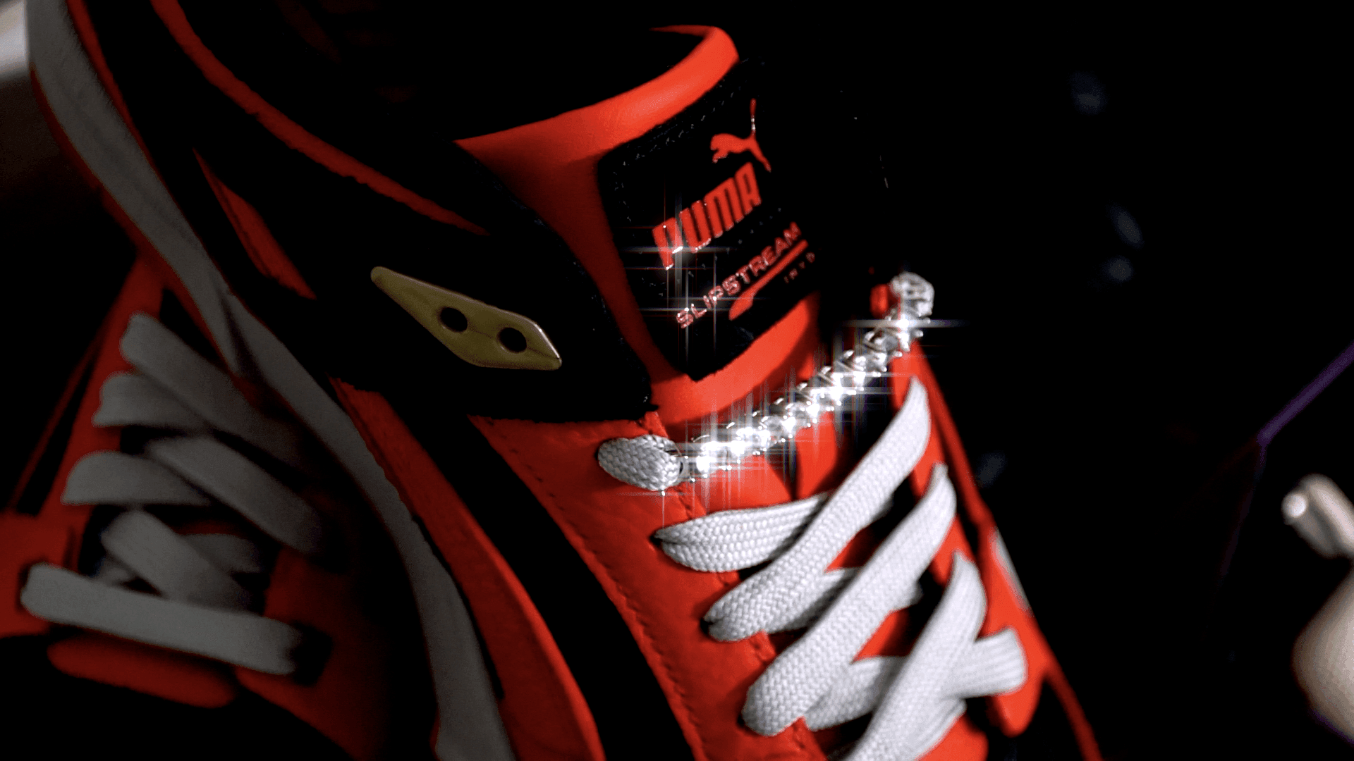 Red and black sneaker with white laces and a sparkling chain detail on the side.